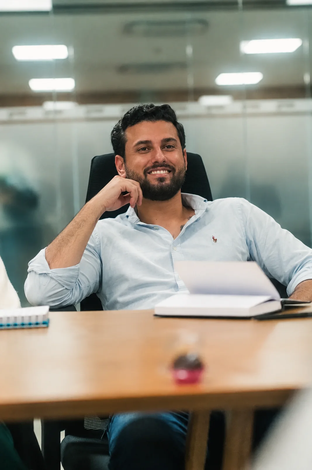 Sócio investidor sorrindo, recostado na cadeira, em reunião no escritório da rede VR